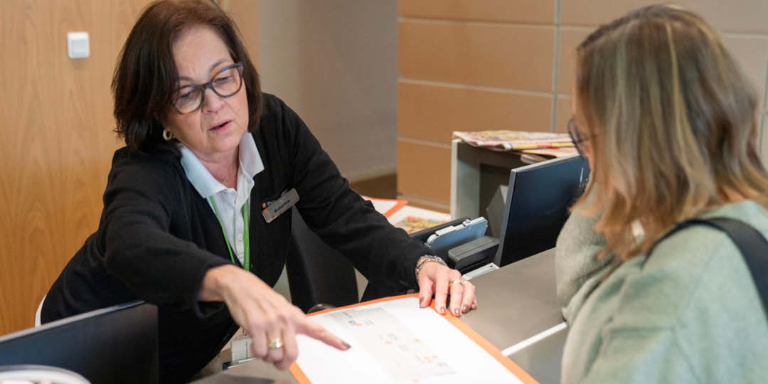 Receptionist pekar på karta och hjälper besökare vid disk.