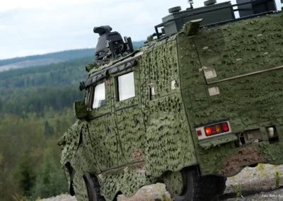 Camouflaged Saab military vehicle in a forest environment during off-road driving.